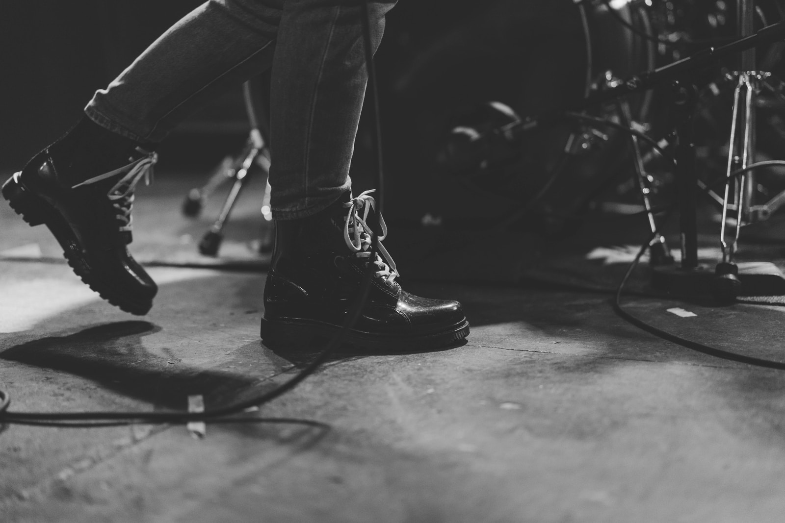 headphonik - person in black leather boots walking beside of drum set
